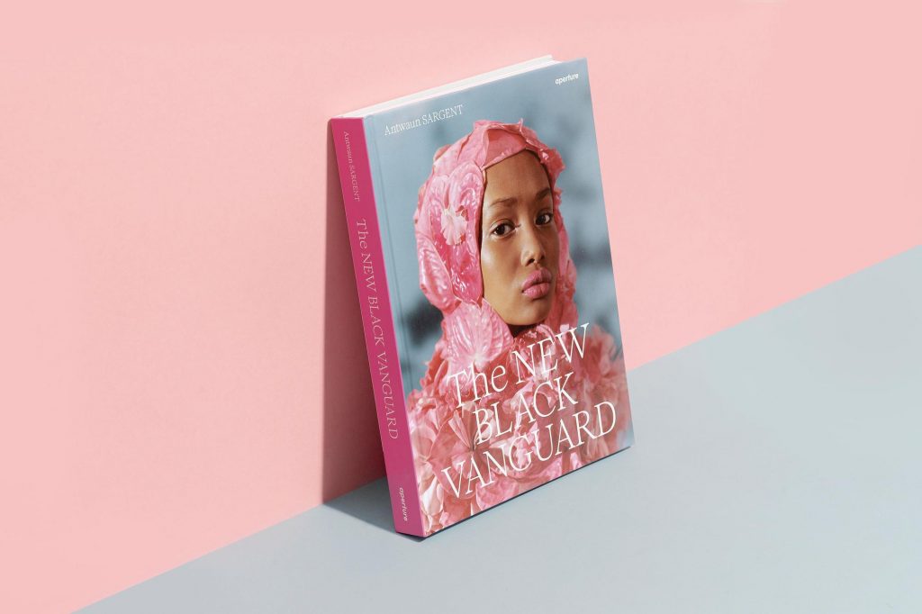 A book cover with a photograph of a women in a headscarf. The book leans against a pink wall.