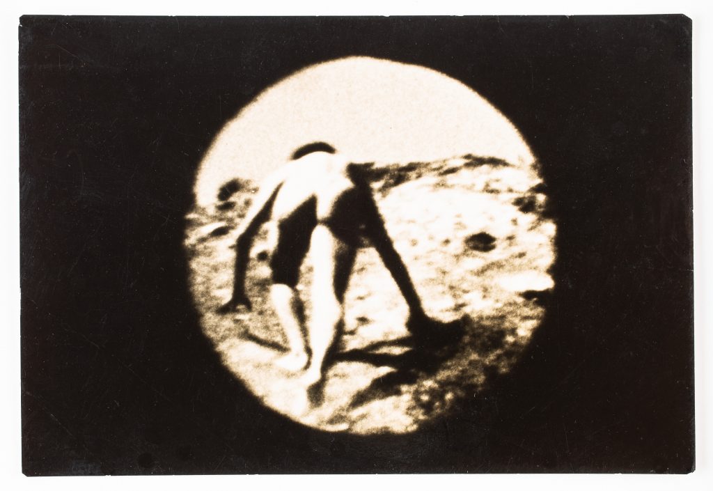 A film still of someone climbing up a rocky landscape.