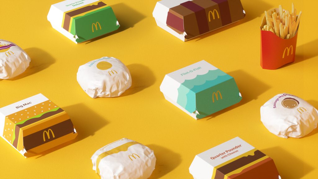 A product shot of McDonald’s meals in minimal, colorful packaging laid out on a yellow background.