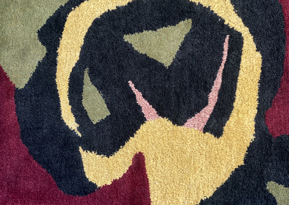 Tufted rug featuring green, yellow, and maroon