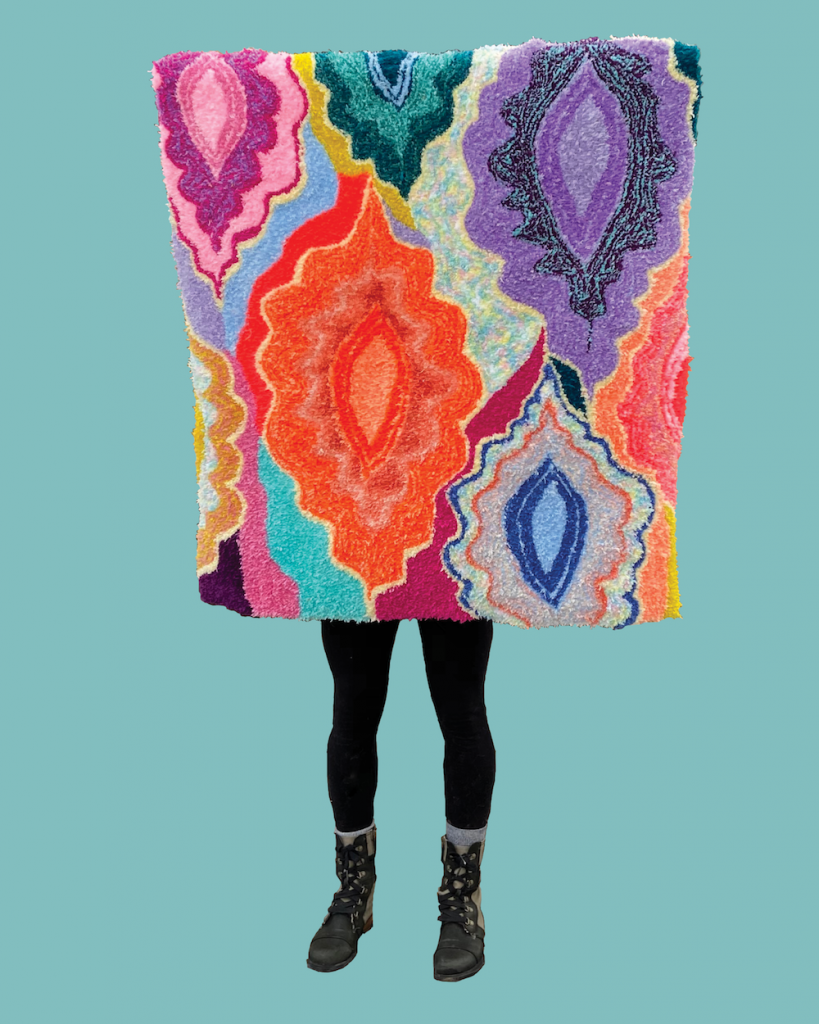 Human holding colorful rug in front of their face