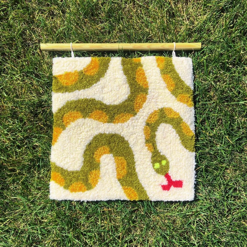 Small tufted rug featuring a snake laying across grass